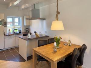 een keuken en eetkamer met een houten tafel en stoelen bij Haus Dünenperle, Ferienwohnung Wanderdüne in Wittdün +7 foto's
