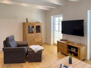 een woonkamer met een stoel en een flatscreen-tv bij Haus Dünenperle, Ferienwohnung Wanderdüne in Wittdün