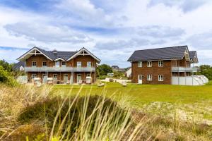 een groot huis op een grasveld naast een huis bij Haus Dünenperle, Ferienwohnung Wanderdüne in Wittdün