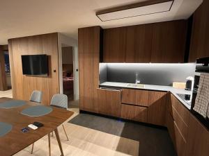 een keuken met houten kasten en een tafel en een televisie bij Mountain Loft - DuLac 33 in St. Moritz