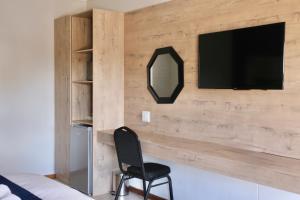 a bedroom with a wooden wall with a tv and a chair at Tuscany Vryburg in Vryburg