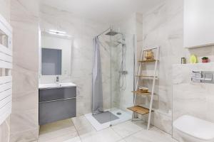 een witte badkamer met douche en wastafel bij Ellington - Studio dans le quartier daffaires in Chatou +6 foto's