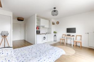 een witte slaapkamer met een bed en een bureau met een televisie bij Ellington - Studio dans le quartier daffaires in Chatou