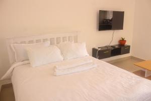 BungomaMiranda suites的白色的床、白色枕头和平板电视