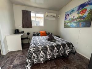 a bedroom with a bed with a black and white comforter at Bushchooks Travellers Village in Bororen