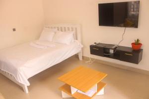 BungomaMiranda suites的一间卧室配有一张带电视和桌子的床。