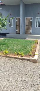 a house with a grass yard in front of it at Gravity Apartments & Lodges in Mazabuka