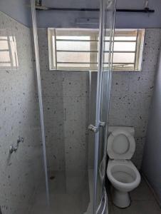 a bathroom with a toilet with a glass shower stall at Gravity Apartments & Lodges in Mazabuka +9 photos