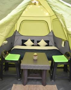 a bed and two chairs in a tent at Araku Mountview Camping Resort in Araku +8 photos