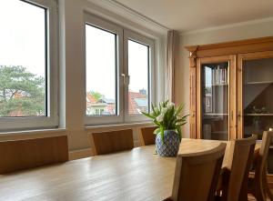 een eetkamer met een houten tafel en ramen bij Lichtdurchflutete Dachgeschosswohnung in Uninähe in Oldenburg