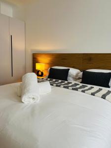 una camera da letto con un grande letto bianco con asciugamani sopra di Black Pearl Oasis a Città del Capo Altre 4 foto