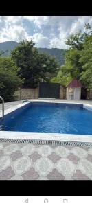 a large blue swimming pool with a tile floor at Gabala villa in Gabala