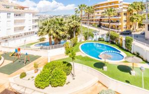 an apartment with a pool and palm trees and buildings at Calamora I by Sun & Sea Homes in Moraira
