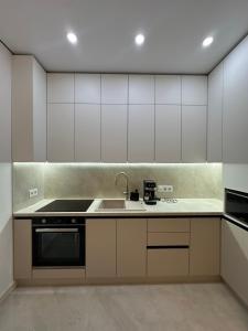 eine Küche mit weißen Schränken und einer Spüle in der Unterkunft ЖК Варшавський - Balance Home in Ternopil + 13 Fotos