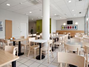 a dining room with tables and chairs and a tv at B&B HOTEL Grenoble Centre Alpexpo in Grenoble