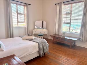 ein Schlafzimmer mit einem Bett, einem Tisch und einem Spiegel in der Unterkunft Sunrise & Sunset Haven in Mossel Bay