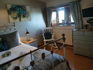 a bedroom with a bed and a chair and a window at Walls Clough in Rossendale