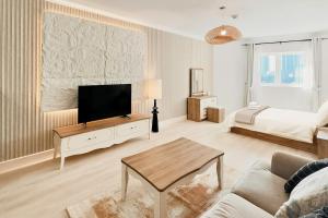 a living room with a television and a bed at Stylish Furnsihed Apartments Opposite Five Hotel In JVC in Dubai