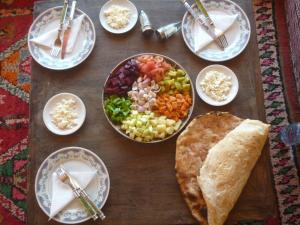 a wooden table topped with a cutting board filled with food at Auberge Migusta in Skoura