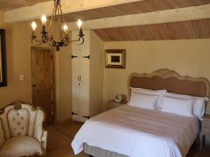 een slaapkamer met een wit bed en een stoel bij Winnaarspoort Lodge in Hydro