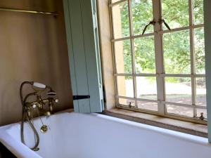 een badkuip met een douche naast een raam bij Winnaarspoort Lodge in Hydro +91 foto's