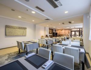 a dining room with tables and white chairs at Hotel Terra Nova in Novalja