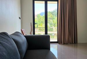een woonkamer met een bank en een groot raam bij Villa Lyn Kai Bae in Khlaung Phai Bae