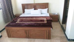 une chambre avec un grand lit avec une tête de lit en bois dans l'établissement All khair hotel, à Murree