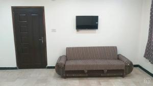 une chaise assise dans une pièce avec une télévision murale dans l'établissement All khair hotel, à Murree