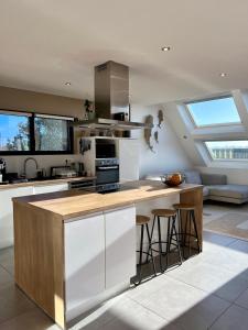 een keuken met witte kasten en een aanrecht met krukken bij La maison des Macareux - 5 min des plages in Lamballe Armor