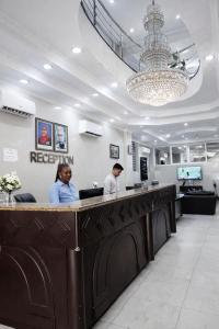 zwei Personen stehen an einem Empfangstresen in einem Salon in der Unterkunft Rainbow Hotel in Daressalam