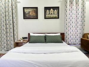 een slaapkamer met een wit bed en een stoel bij Flora A rooftop with serenity and peace in Jaipur