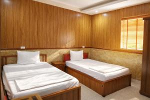 two beds in a small room with wooden walls at Quỳnh Vy Hotel Thái Nguyên in Thái Nguyên