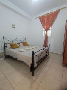 a bed in a white room with a red curtain at Résidence SUN SHINE DJERBA in Midoun +58 photos
