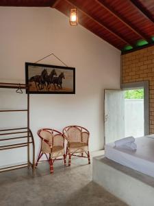 een slaapkamer met een bed, twee stoelen en een tafel bij Galle Light Villa in Galle
