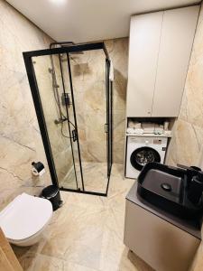 een badkamer met douche en wasmachine bij Ūla Apartments in Mažeikiai +5 foto's