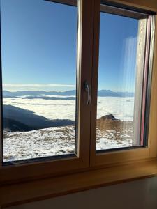 ein Fenster mit Blick auf ein schneebedecktes Feld in der Unterkunft Koralpenhaus Schutzhaus in Goding