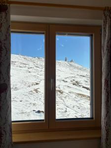 ein Fenster mit Blick auf einen schneebedeckten Hügel in der Unterkunft Koralpenhaus Schutzhaus in Goding