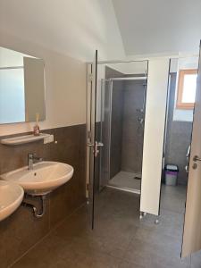 ein Bad mit einer Dusche, 2 Waschbecken und einer Duschkabine in der Unterkunft Koralpenhaus Schutzhaus in Goding