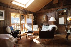 a living room with wooden walls and chairs and a window at Lieu Secret dans les Alpes Suisses in Le Trétien
