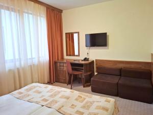 ein Hotelzimmer mit einem Bett und einem Schreibtisch mit einem Fernseher in der Unterkunft Elina Hotel in Pamporowo