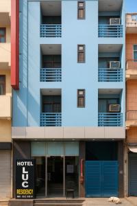 ein Mehrfamilienhaus mit einem blauen Schild davor in der Unterkunft Hotel Earth By Aashiyana in Neu-Delhi