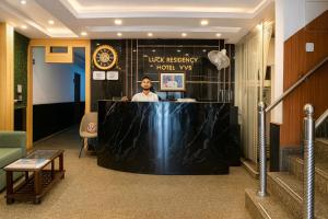 Ein Mann, der an einem Tresen in der Lobby sitzt. in der Unterkunft Hotel Earth By Aashiyana in Neu-Delhi