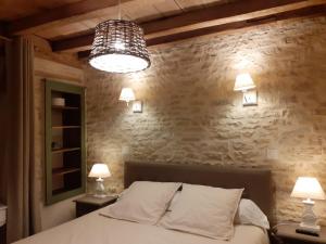 - une chambre avec un lit avec deux lampes et un mur en pierre dans l'établissement La Tour, à Châtillon-sur-Seine