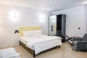 una camera da letto bianca con un letto e una sedia di Oak Villa, Ukulhas a Ukulhas Altre 14 foto