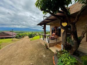 een huis met een stoel op de veranda bij Lanna Maple House in Ban Thap Dua