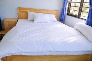 a bedroom with a bed with white sheets and a window at Hà Châu Homestay in Mù Cang Chải