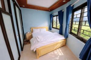 a bed in a room with blue walls and windows at Hà Châu Homestay in Mù Cang Chải