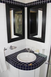 uma casa de banho com um lavatório e 2 espelhos em Illovo Hotel em Joanesburgo