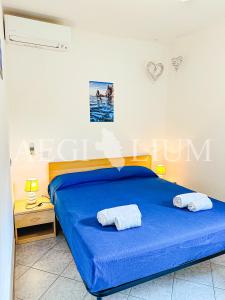 una camera da letto con un letto blu con due asciugamani sopra di Raffaella 3 a Campese Altre 7 foto